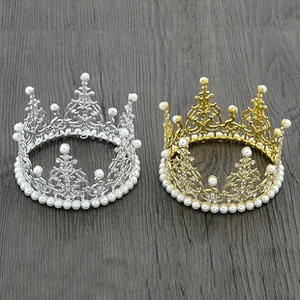 Detailed view of gold and silver hollow metal crowns with pearls on wood background