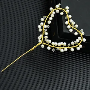 Macro detail of handmade golden heart cake topper with white pearls and crystals