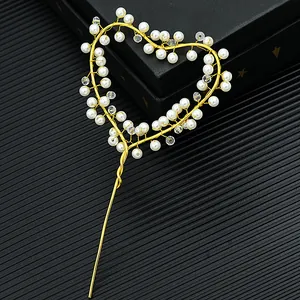 Golden heart cake topper with elegant white pearls and crystals on a dark background