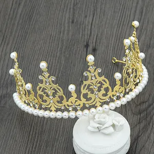Detailed macro of golden crown cake topper with pearls and rhinestones on wood background
