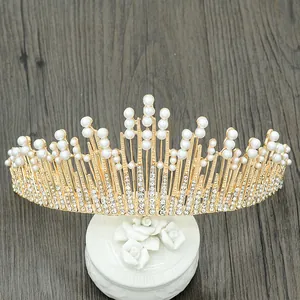 Baroque gold bridal crown featuring white pearls and crystals on decorative stand