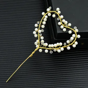 Detailed close-up of golden wire heart cake topper with pearls and crystals