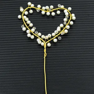 Detail of a handmade golden heart cake topper with elegant white pearls and clear beads
