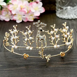 Close-up of golden deer crown with white pearls and rhinestones on wood background