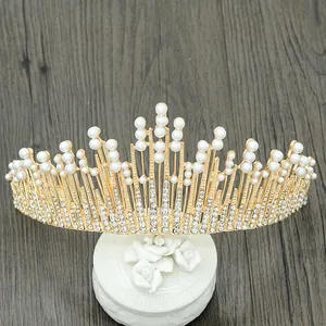 Baroque gold tiara with white pearls and rhinestones on a rustic wood background