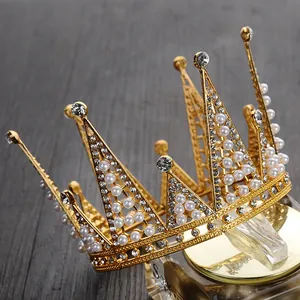 Dettaglio di una corona dorata con perle bianche e cristalli su una base di vetro dorata