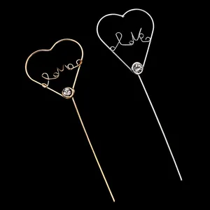 Close-up of heart-shaped gold and silver cake toppers with Love script and rhinestone