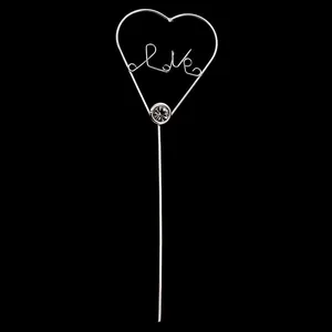 Silver metal heart cake topper with Love lettering and rhinestone on a black background