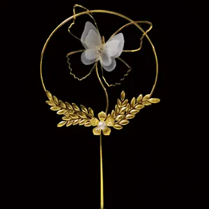 Golden iron cake topper with translucent butterfly, rhinestone flower and pearl details