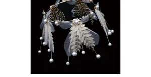 Detailed close-up of golden leaf crown with pearls and white tulle on black background