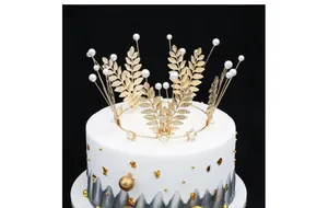 Macro shot of golden leaf crown with pearls on white cake against black background