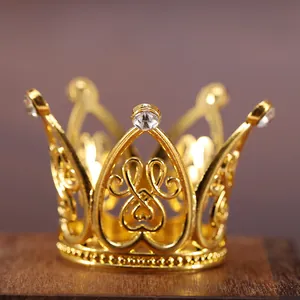 Gros plan de mini couronne dorée avec motif cœur et strass sur surface en bois