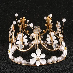 Detalle de corona de flores dorada artesanal con perlas blancas y cristales finos