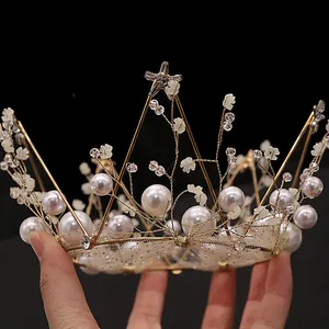 Elegant gold metal crown with pearls, white flowers, and mesh lace for cake decoration