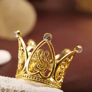 Vue macro détaillée d'une mini couronne dorée pour gâteau avec strass et motifs cœurs