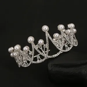 Sparkling silver crown with white pearls and rhinestones on black rock background