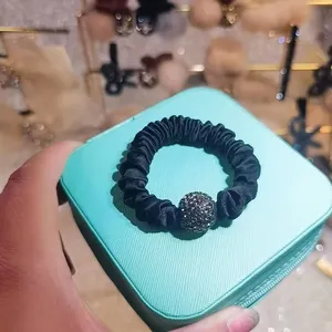 Detail of black satin scrunchie with sparkling grey rhinestone ball decoration