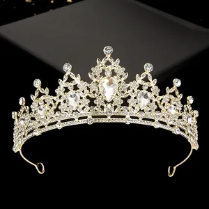 Detailed close-up of golden bridal crown with sparkling rhinestones and drop-shaped crystal