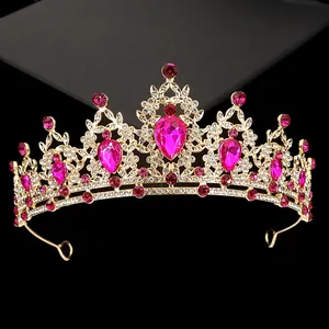 Close-up of golden crown featuring large teardrop rose red rhinestones and white crystals