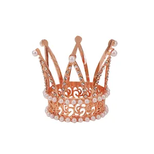 Rose gold mini crown cake topper with sparkling crystals and white pearls on white background