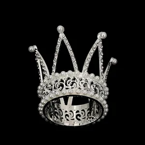Close-up of silver rhinestone crown with pearls and intricate hollow carved patterns