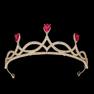 Close-up of golden bridal crown featuring red pear-shaped rhinestones and crystal inlay