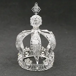 Detailed close-up of a silver filigree hollow crown featuring intricate heart patterns