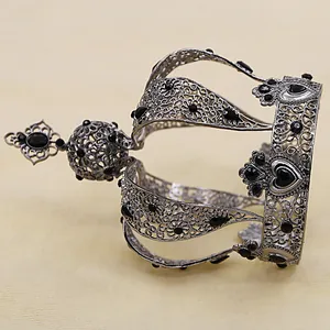Detail of silver hollow metal crown with intricate floral filigree and black gemstones