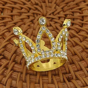 Golden crown cake decoration with sparkling white rhinestones on brown woven background