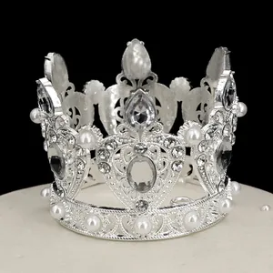 Detailed view of silver crown topper with sparkling rhinestones and white pearls