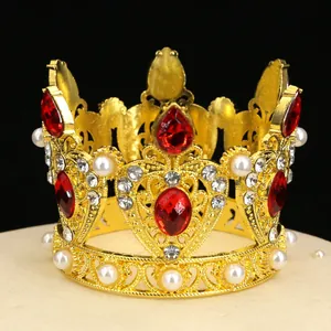 Macro shot of gold crown cake topper with red rhinestones and pearls on black backdrop