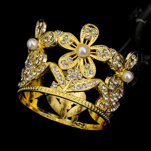 Dettaglio di corona dorata con perle bianche e cristalli su sfondo nero
