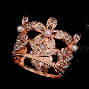 Dettaglio di una mini corona in lega oro rosa con strass bianchi e perle su fondo nero