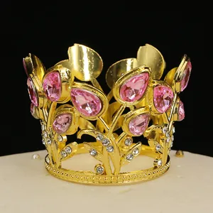 Macro detail of golden crown cake topper with pink teardrop crystals and small rhinestones