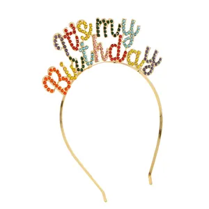 Dettaglio degli strass colorati su un cerchietto per feste dorato con scritta It's My Birthday