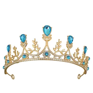 Elegante tiara dorata con cristalli blu a goccia e diamanti bianchi su sfondo bianco