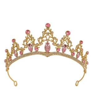 Goldene Brautkrone mit rosa Kristallen und weißen Strasssteinen auf weißem Grund