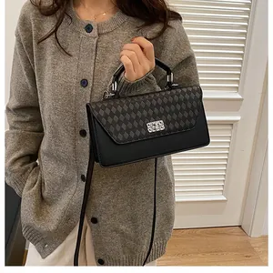 Détail d'un sac à main noir vintage avec rabat à losanges et fermoir rotatif argenté