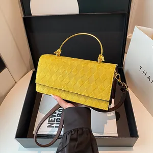 Gele suède crossbodytas met ruitpatroon en gouden handvat in een geschenkverpakking