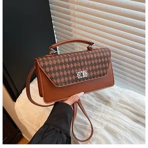 Détail d'un sac bandoulière marron avec motif à losanges et boucle argentée