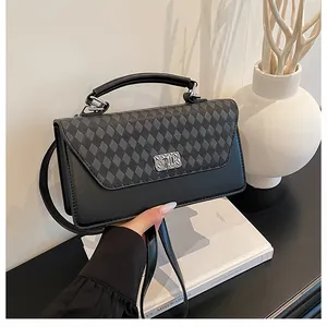 Détail du motif matelassé gris sur un sac à main en cuir PU noir avec fermoir rotatif