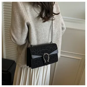 Detail of leopard print flap bag featuring a silver horseshoe buckle and chain strap