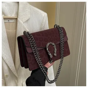 Detailed view of burgundy leopard print suede bag with metal tiger head buckle and chain