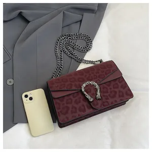 Macro detail of burgundy leopard print texture and silver tiger head metal buckle