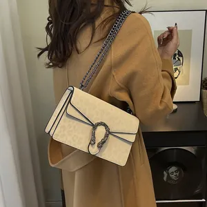 Leopard print crossbody bag with chain strap and tiger head buckle on khaki wool coat