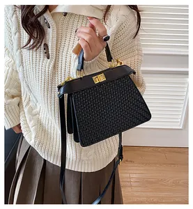 Close-up of black woven leather bag with gold metal turn-lock and elegant top handle