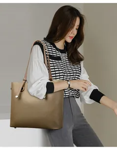 Détail de la texture d'un grand sac cabas en cuir souple kaki porté par un mannequin chic