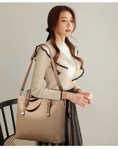 Gros plan d'un sac cabas en similicuir beige avec texture grainée et anses marron foncé
