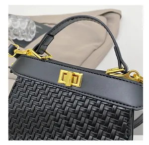 Detail of black woven handbag featuring a gold rectangle twist-lock and smooth leather handle