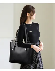 Détail d'un grand sac cabas noir en cuir grainé porté par un mannequin avec style
